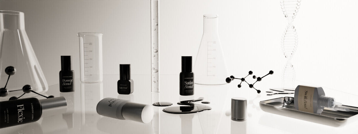 Professional lash glue bottles alongside scientific chemistry objects to illustrate the complex chemical process and curing variables of lash adhesive.