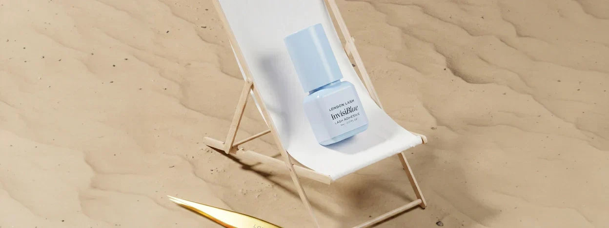 Invisiblue eyelash extension adhesive placed on a beach chair, showcasing summer lash glue care and humidity control.