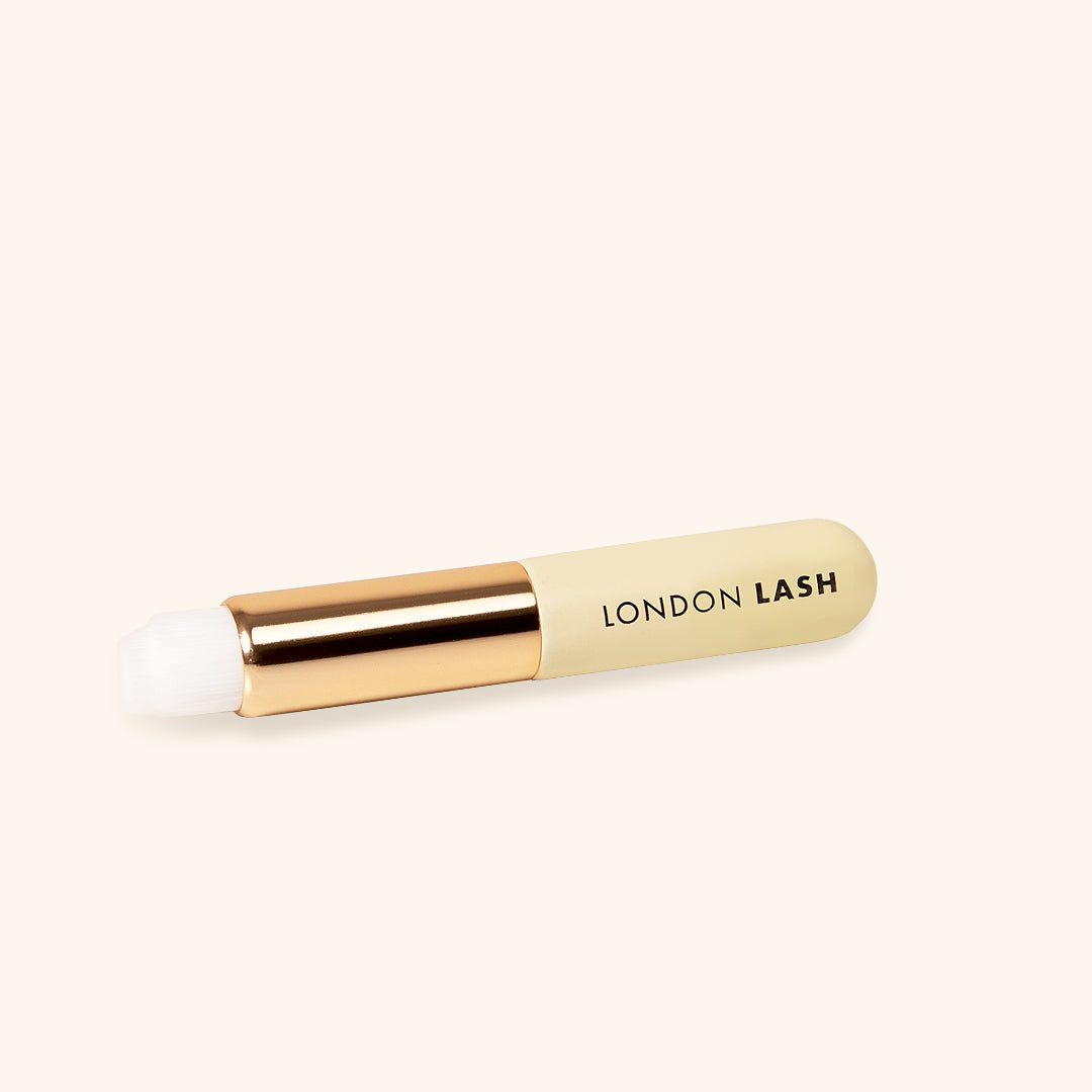 lash cleansing brush with white soft fibers and metallic gold and wooden beige handle