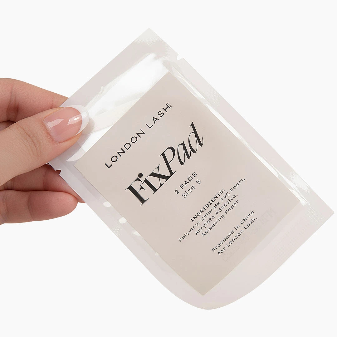 Hand holding a 'London Lash FixPad' packaging on a white background