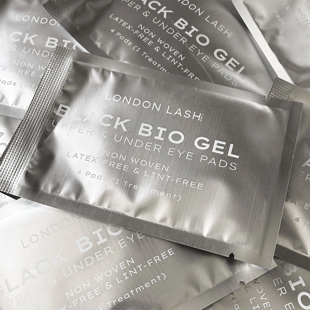 Multiple silver foil packets of London Lash Black Bio Gel non-woven under eye pads arranged on a light gray surface.