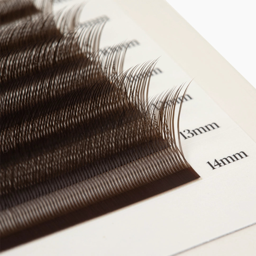 Extreme macro close-up of dark brown Kitten Lash extensions on length-marked strips showing fiber density and curl structure.
