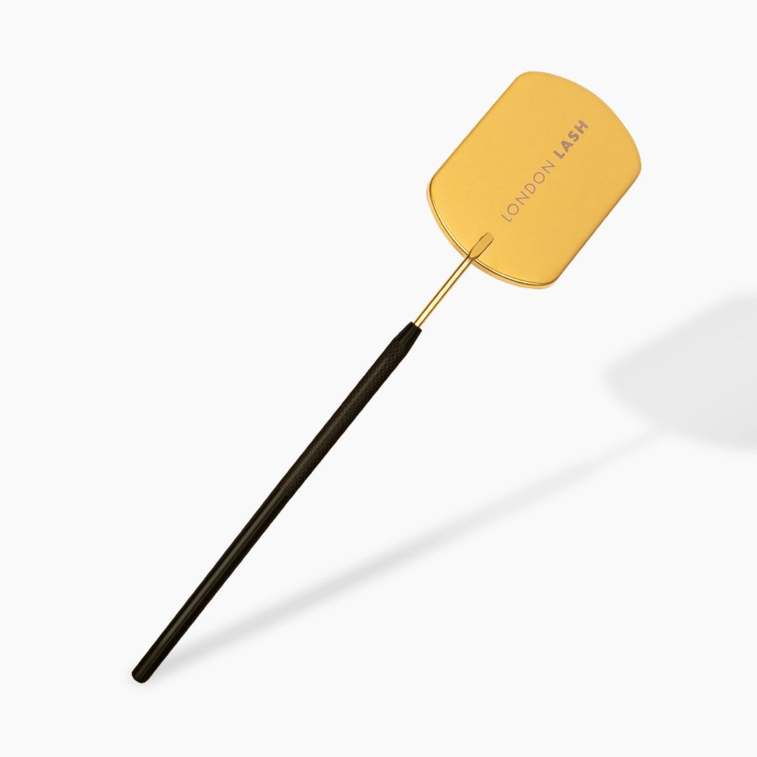 Yellow lash mirror with black handle on a white background