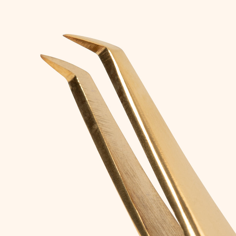 close up to curved thin tip of volume professional tweezers in gold colour 